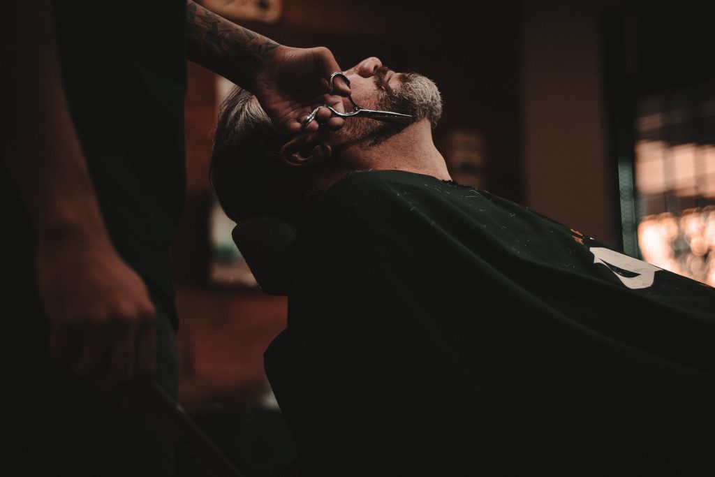 Homme qui se fait tailler la barbe dans un barber shop