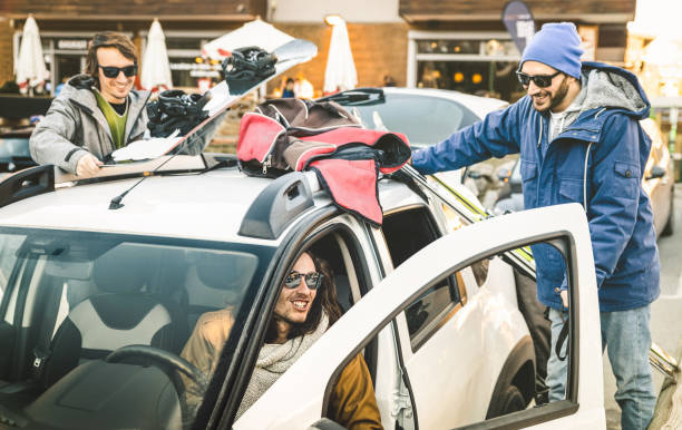 Trois jeunes hommes en tenue de ski qui montent dans une voiture