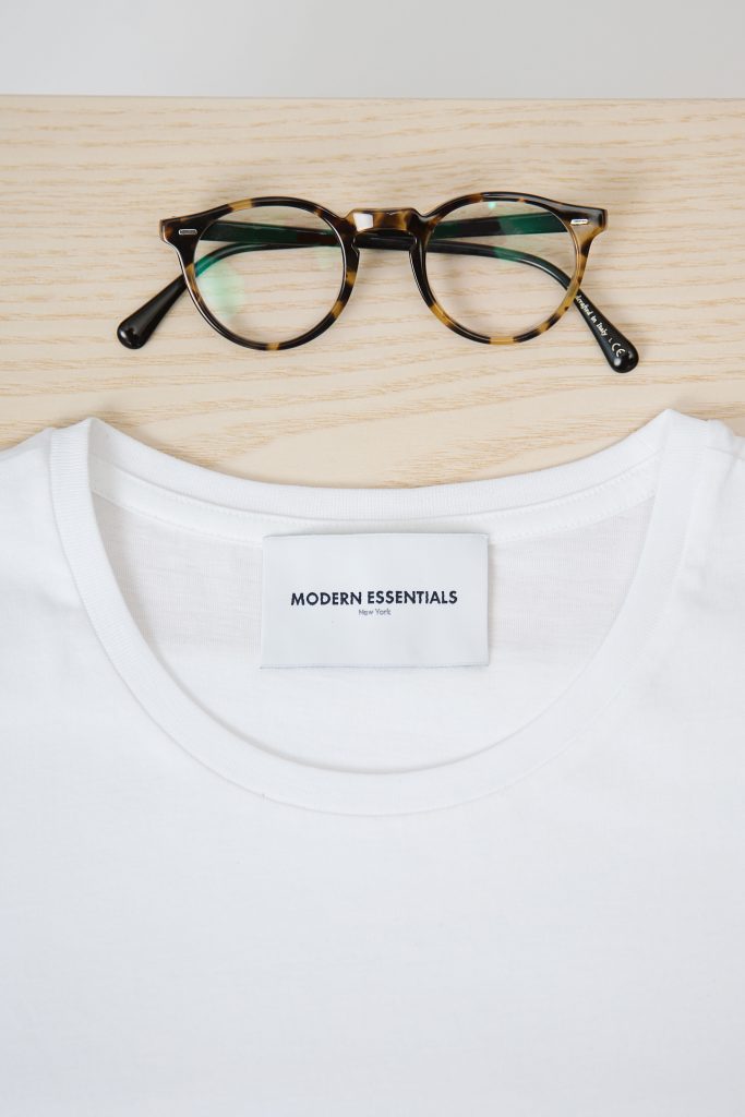 Gros plan sur un t-shirt blanc à col rond et une paire de lunettes de vue moderne