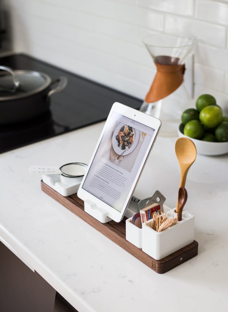 ustensiles de cuisine et tablette avec la recette sur un support en bois