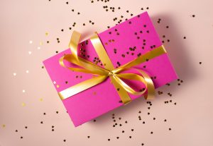 paquet cadeau avec papier rose et ruban doré et paillettes parsemées